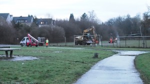 Bagger fährt durch die Grünanlage auf den Sportplatz